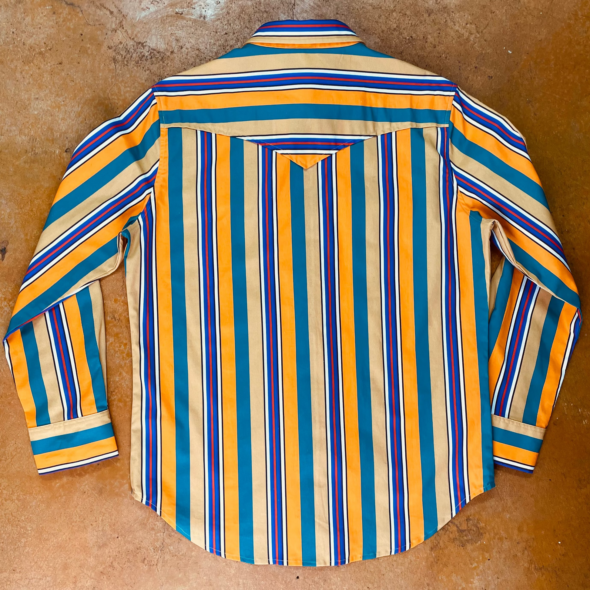 Striped shirt with blue, orange, and green pattern on a brown surface